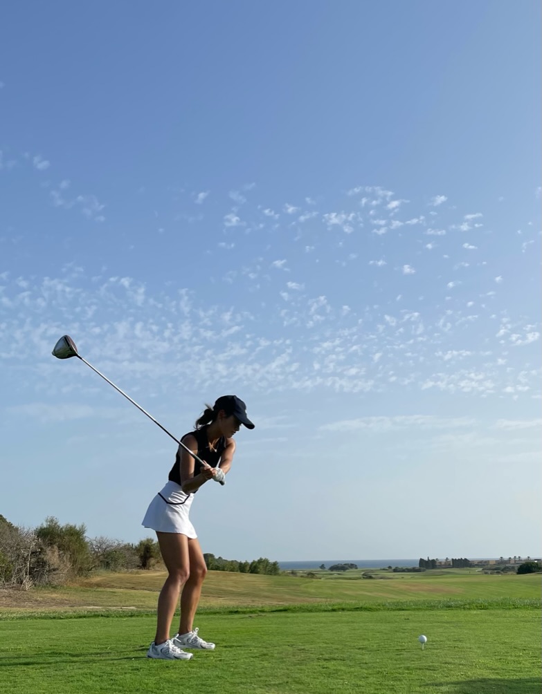A woman enjoying a round of golf on a scenic, sun-drenched course, an example of a leisure activity arranged on a bespoke Travellé tour.
