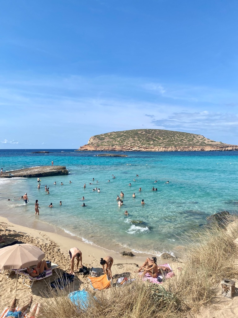 Sunbathers relaxing on a beautiful beach with turquoise waters, a destination available through a personalized Travellé travel itinerary.