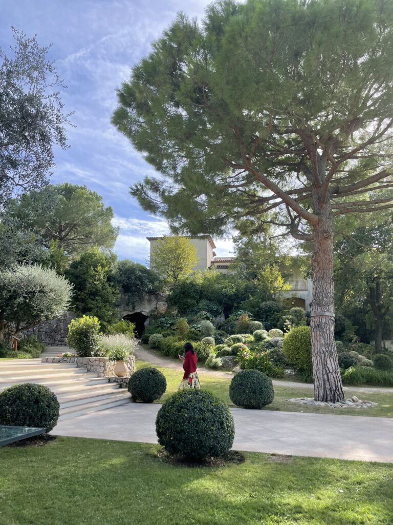 A serene path through the manicured gardens of a private estate, representing the "design-forward villas" featured in Travellé itineraries.