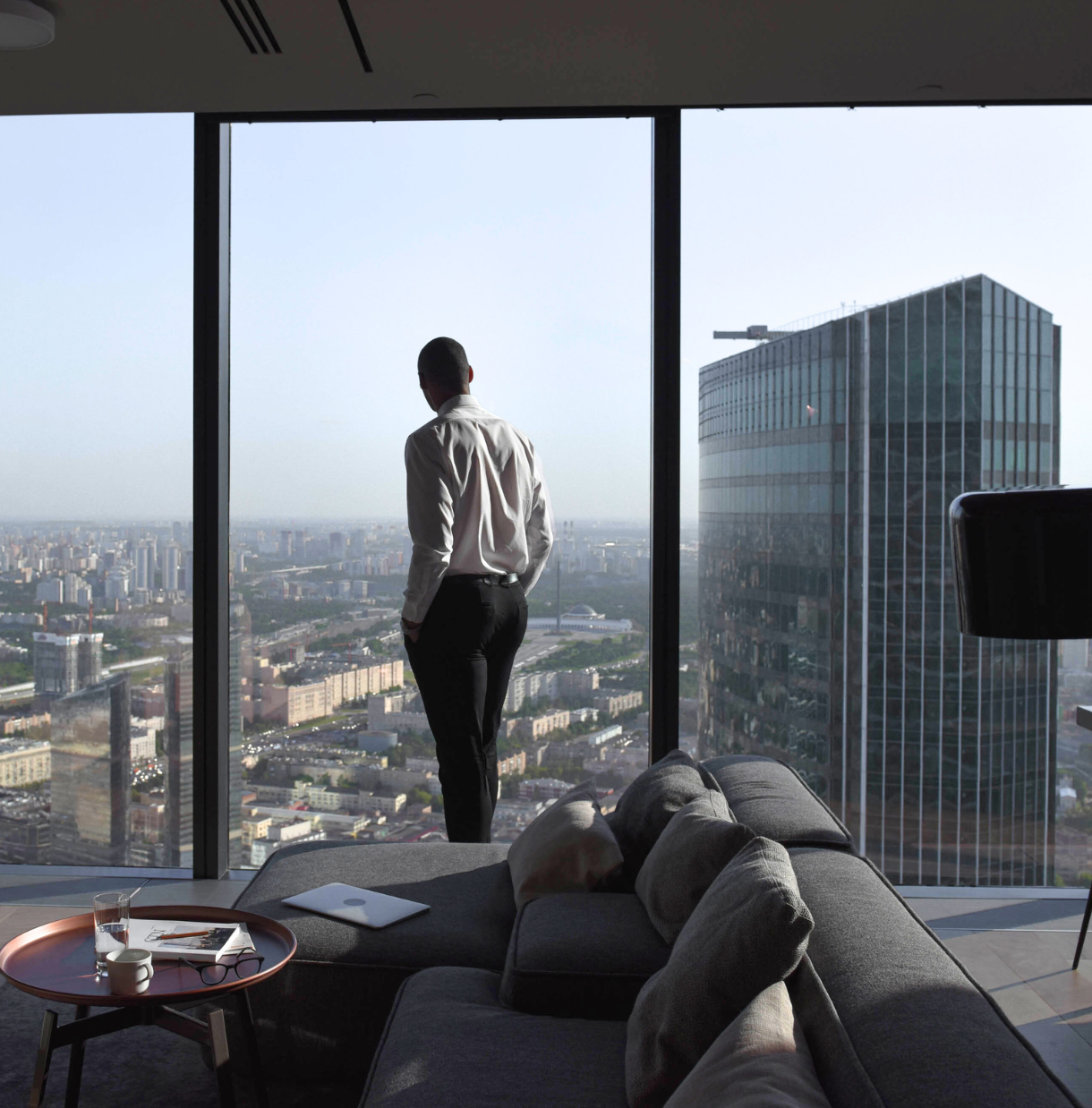 A man looking out from his high-rise apartment over the city, reflecting on his "vision for the future" in his "House of Dreams."
